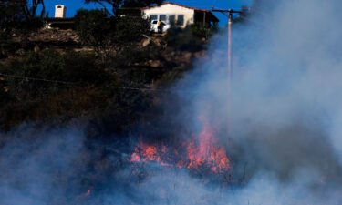 A wildfire raging through Southern California's coastal mountains threatened ranches and rural homes and kept a major highway shut down Wednesday as the fire-scarred state faced a new round of dry winds that raise risk of flames.