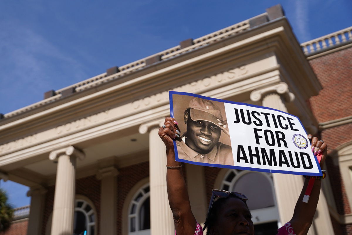 <i>Sean Rayford/Getty Images</i><br/>A demonstrator holds a sign at the Glynn County Courthouse as jury selection begins in the trial of Arbery's shooting death on October 18