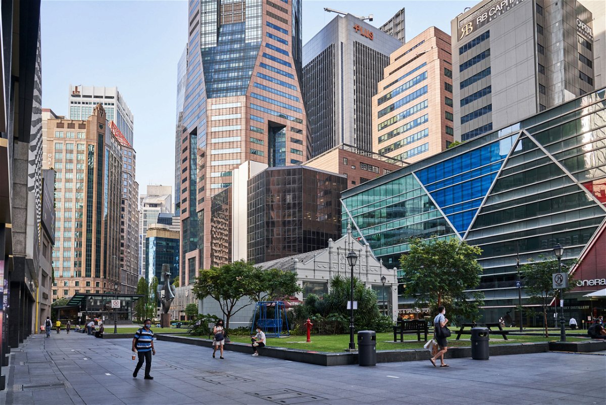 <i>Lauryn Ishak/Bloomberg/Getty Images</i><br/>Singapore will extend its Covid-19 restrictions for another month after the city-state reported 18 new deaths from the disease. Pedestrians are seen here passing through a near empty Raffles Place in the central business district of Singapore