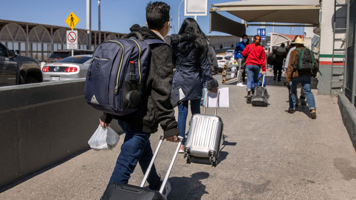 <i>John Moore/Getty Images</i><br/>The Biden administration is preparing to revive in mid-November a Trump-era border policy that forces migrants to stay in Mexico until their US immigration court date. Asylum seekers are shown here crossing an international bridge from Mexico into the United States on March 17