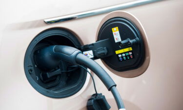 A charging plug connected to a Fiat 500e electric automobile outside a Fiat showroom