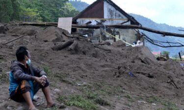 A resident sits near houses at the scene of a landslide triggered by a 4.8 magnitude earthquake at Trunyan village in Bangli