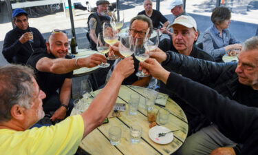 People enjoy a drink at a busy Lygon Street cafe in Melbourne on October 22