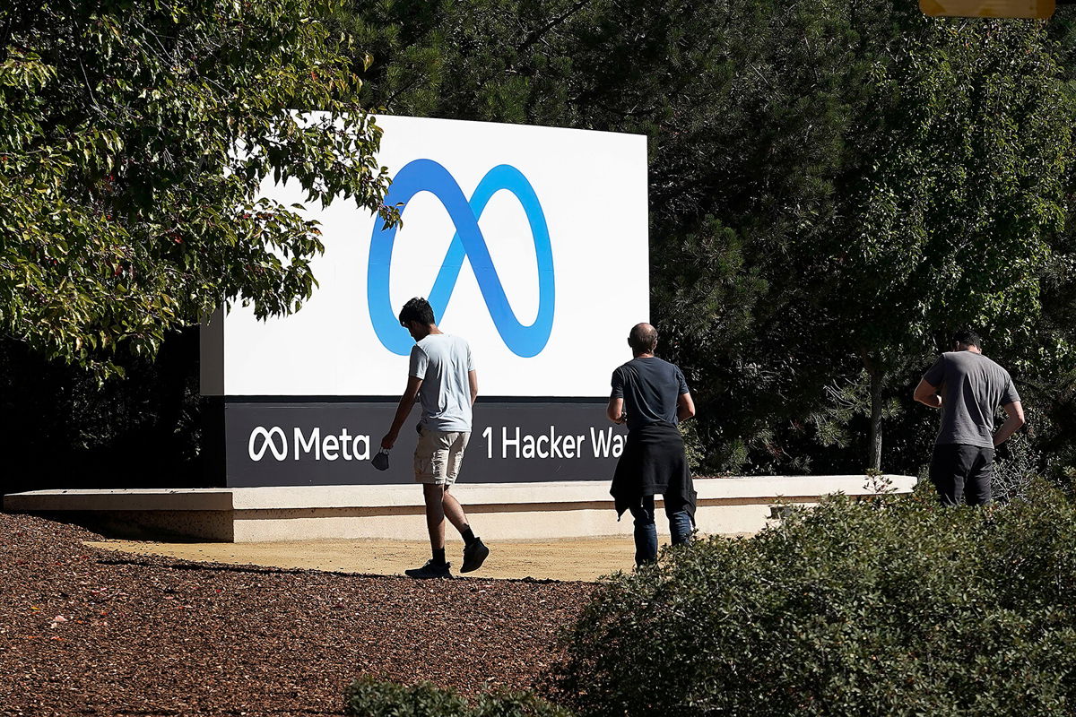 <i>Tony Avelar/AP</i><br/>Facebook employees take a photo in front of new Meta Platforms Inc. sign outside the company headquarters in Menlo Park