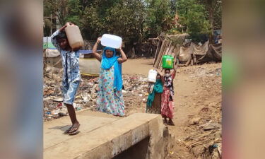 Residents carrying cartons of water to the Ambedkar Nagar slum in Mumbai