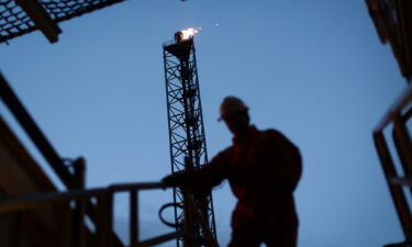 An employee walks down stairs in view of a gas burn off venting pipe on the Armada gas condensate platform