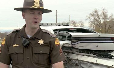 Utah Highway Patrol Sgt. Devyn Gurney speaks with members of the media on Thursday in front of his mangled patrol car. Gurney was struck by it in 2017 after it was rear-ended while he was conducting a traffic stop.
