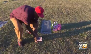 A man plants a flag at a veterans cemetery in Grand Prairie