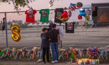 Concert attendees Isaac Hernandez and Matthias Coronel watch Jesus Martinez sign a remembrance board at a makeshift memorial on November 7