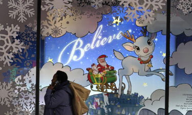 A shopper carries bags over her shoulder while passing a holiday display window outside the Macy's store in the Downtown Crossing district