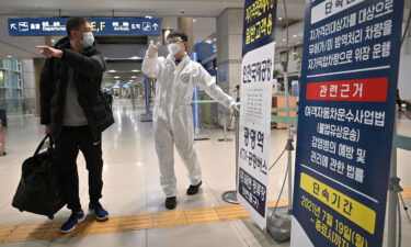 Global stocks and oil prices are falling again after a brief respite from the heavy sell-off triggered by the emergence of the Omicron coronavirus variant as a staff member wearing protective equipment guides a traveler at the arrival hall of Incheon International Airport on November 30 in South Korea.