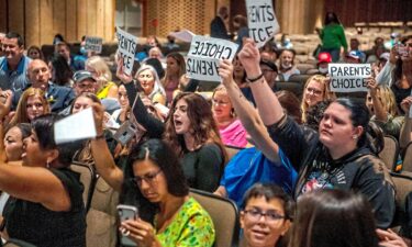 People hold signs and chant during a meeting of the North Allegheny School District school board regarding the district's mask policy