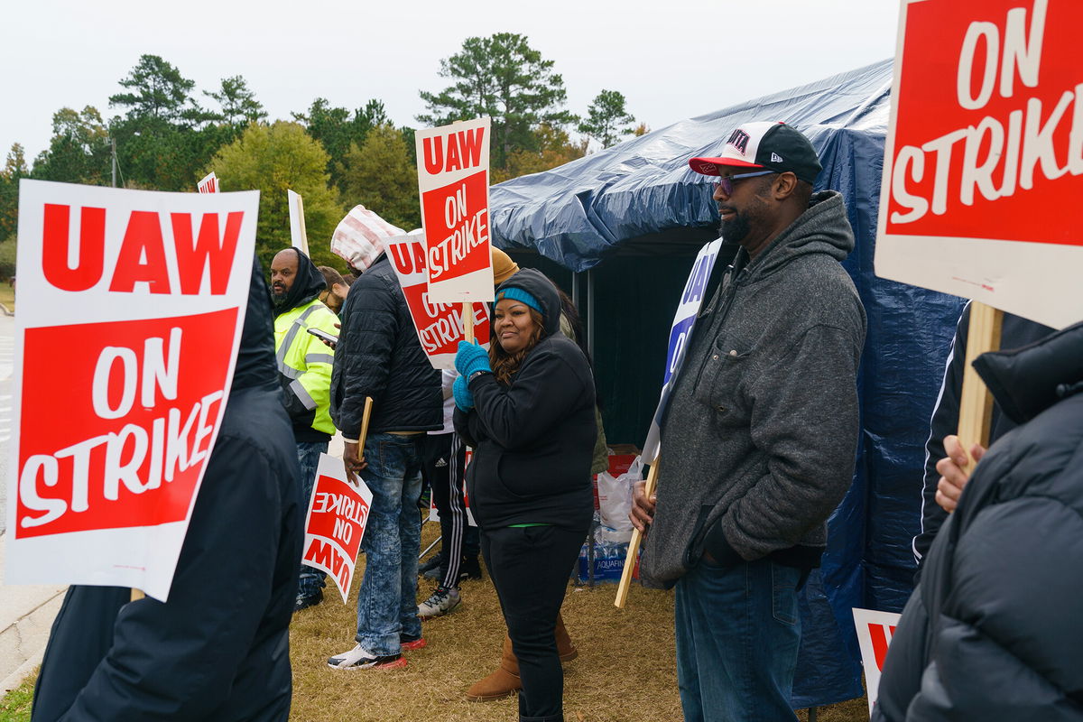 <i>Elijah Nouvelage/Bloomberg/Getty Images</i><br/>Workers hold signs during a strike outside the John Deere Regional Parts Distribution facility in McDonough