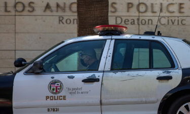 A member of the LAPD sits inside his squad car