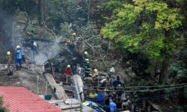 Firemen and rescue workers try to control the fire in the burning debris of an IAF Mi-17V5 helicopter crash site in Coonoor