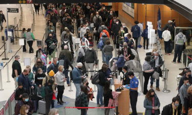 Travelers wear masks as they wait in a line for a TSA security check