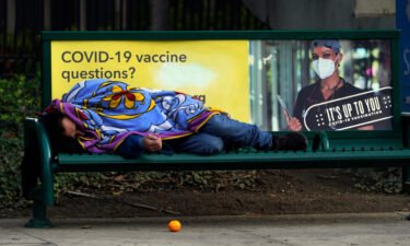 A homeless person sleeps on a bench in downtown Los Angeles