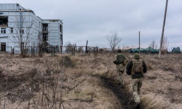 Ukrainian soldiers walk toward a destroyed building on the front line on December 8