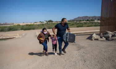 A Cuban family seeking asylum in the United States cross an open section of the border wall at the US-Mexico border in Yuma