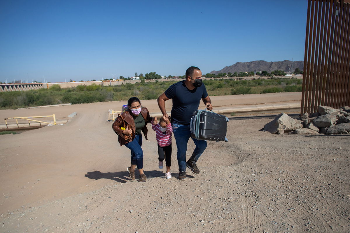 <i>Apu Gomes/Getty Images</i><br/>A Cuban family seeking asylum in the United States cross an open section of the border wall at the US-Mexico border in Yuma