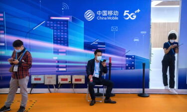 Attendees use their smartphones near a booth for Chinese telecom provider China Mobile at the PT Expo in Beijing