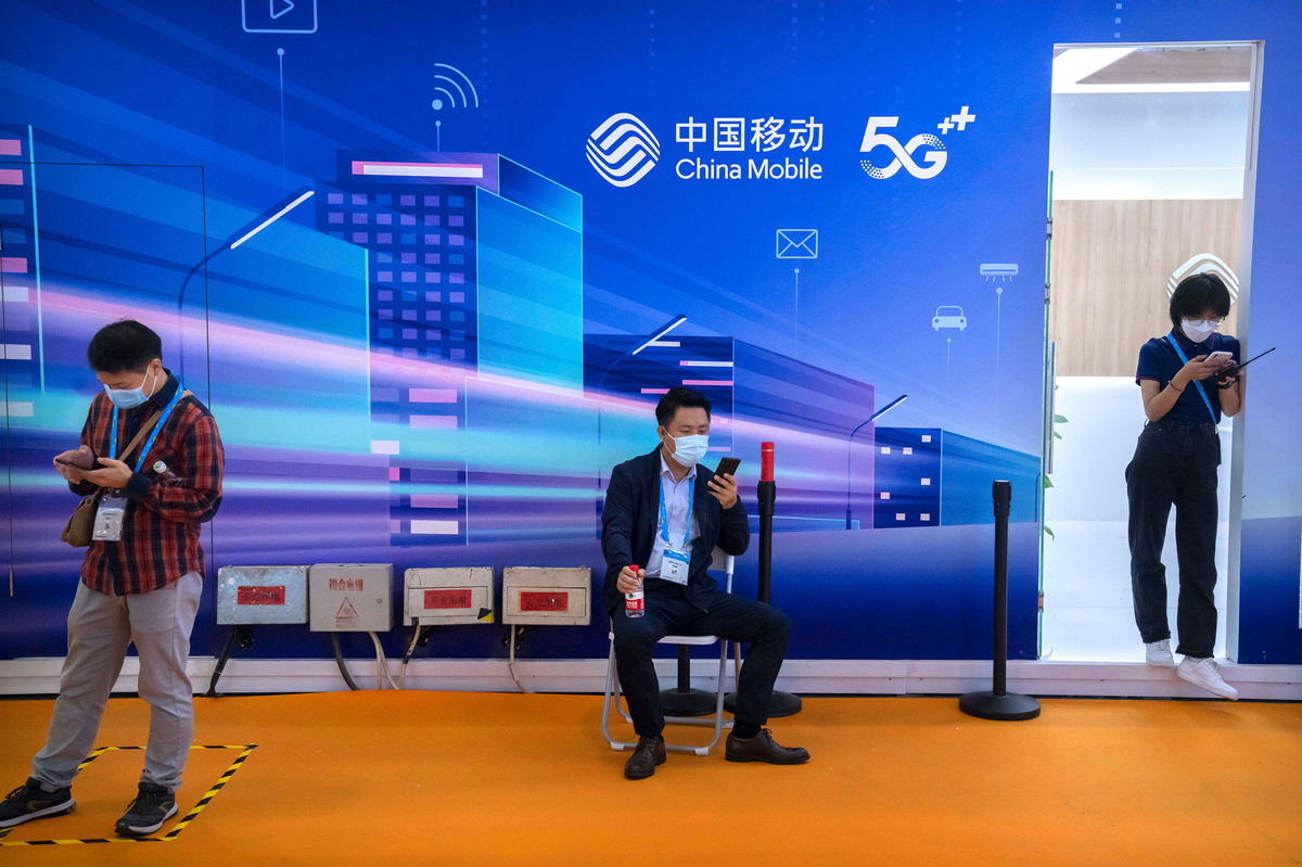 <i>Mark Schiefelbein/AP</i><br/>Attendees use their smartphones near a booth for Chinese telecom provider China Mobile at the PT Expo in Beijing