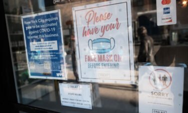 A sign on the door of a coffee shop in Manhattan asks for proof of vaccination and the wearing of a mask on the day that a mask mandate went into effect in New York on December 13.