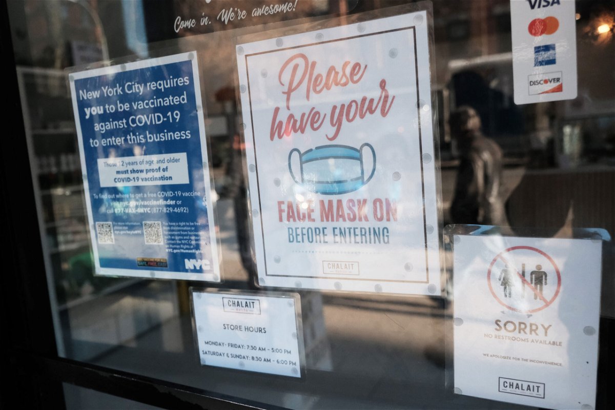 <i>Spencer Platt/Getty Images</i><br/>A sign on the door of a coffee shop in Manhattan asks for proof of vaccination and the wearing of a mask on the day that a mask mandate went into effect in New York on December 13.