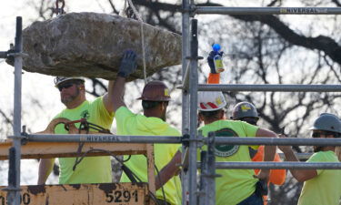 Workers guide a stone containing a time capsule that was placed in 1887.