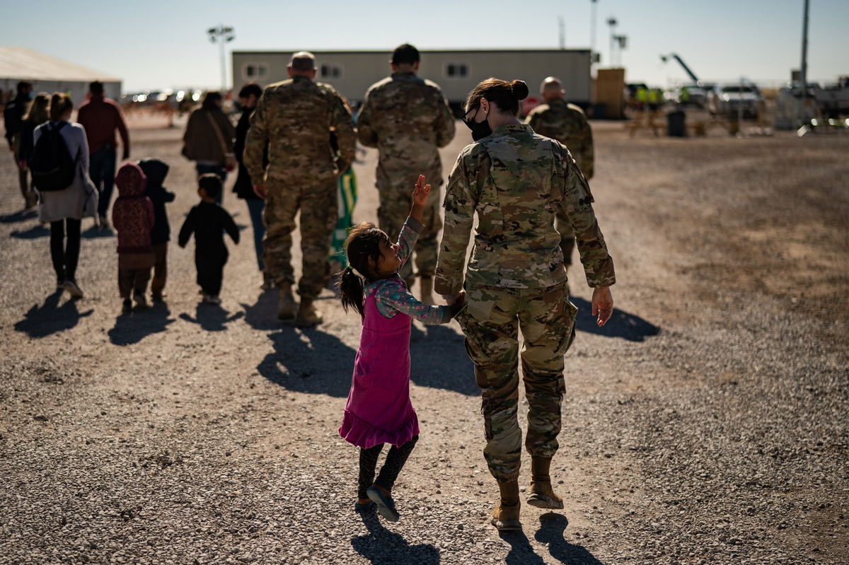 <i>Salwan Georges/The Washington Post/Getty Images</i><br/>A U.S. military service member hold the hands of an Afghan girl at Holloman Air Force Base in Alamogordo