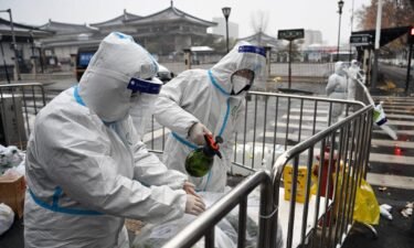 China tightens Xi'an lockdown as city reports highest daily Covid-19 cases in nearly 2 years. Staff members disinfect packed vegetables at a residential area under quarantine in Xi'an on December 25.