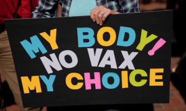 You can collect unemployment benefits in these states if you lose your job because of vaccine mandates. A person is seen holding a sign as several hundred anti-mandate demonstrators rally outside the Capitol on November 16