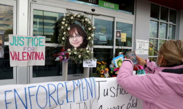 A woman stands at a memorial for Valentina Orellana-Peralta at the door of the Burlington where she was killed