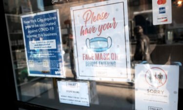 A sign on the door of a coffee shop in Manhattan asks for proof of vaccination and the wearing of a mask on December 13