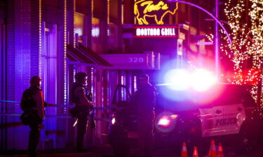 Police stand outside the Belmar shopping center where suspect who claimed five lives was shot and killed on December 27