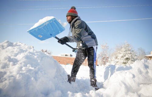 Bonny Obutu shovels snow off his sidewalk in West Des Moines