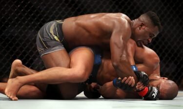 Ngannou grapples on the ground with Gane.