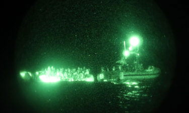 The crew of the Sentinel-class USCGC Glen Harris aboard a small boat assess an overloaded raft taking on water carrying migrants in the Atlantic Ocean prior to their subsequent rescue Jan. 5