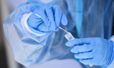 A healthcare worker places a test swab into solution for a PCR Covid-19 test at a Reliant Health Services testing site in Hawthorne