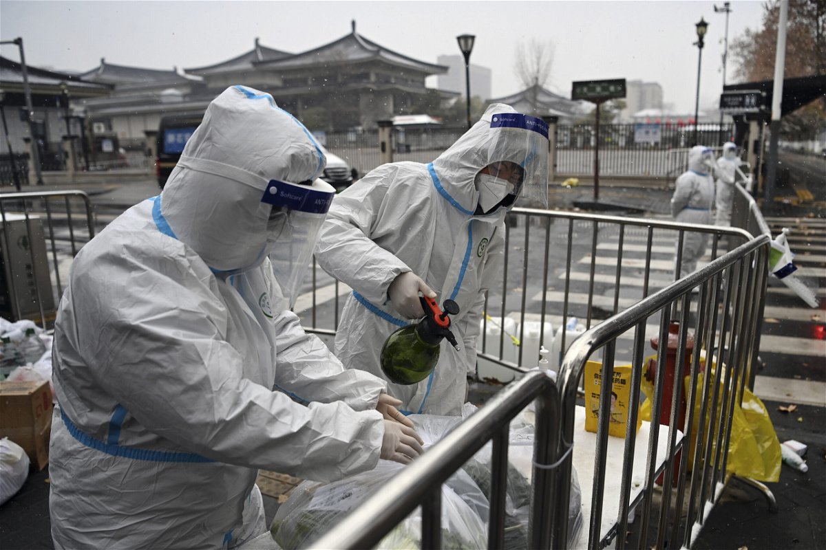 <i>Tao Ming/Xinhua/AP</i><br/>Workers disinfect packed vegetables at a residential area under quarantine in Xi'an