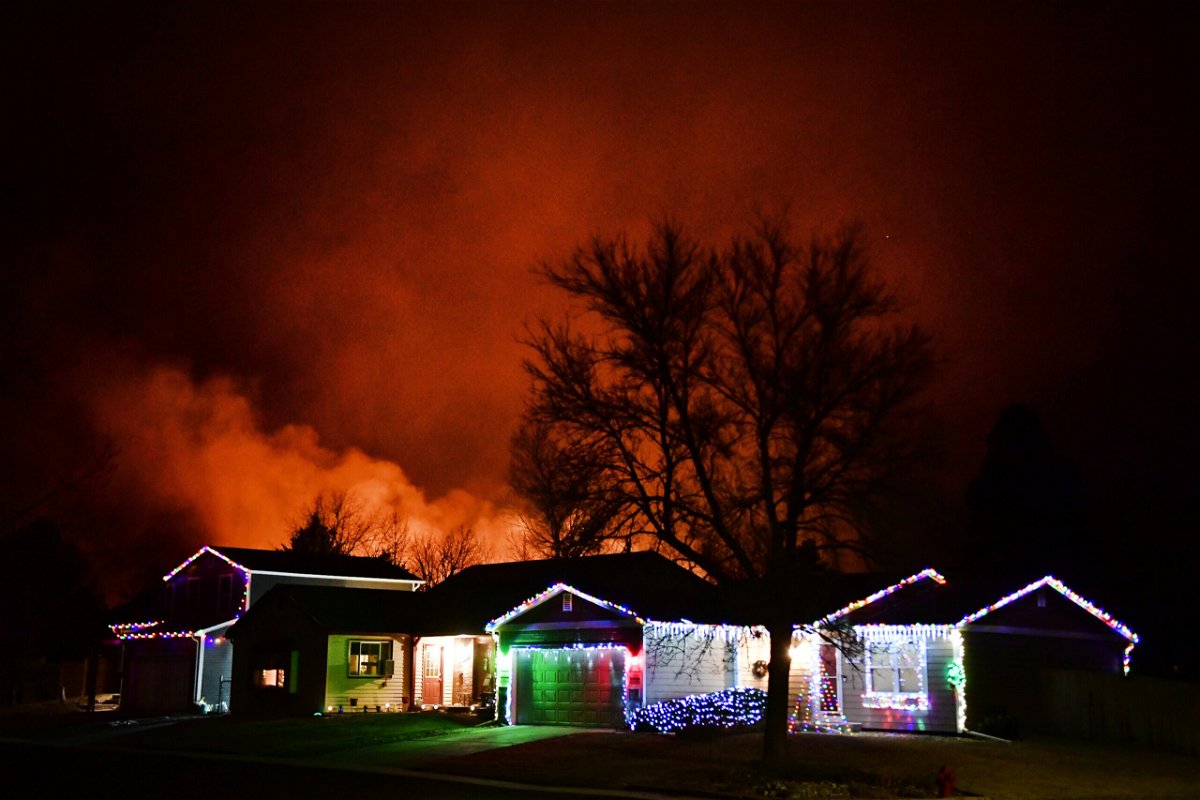 <i>Helen H. Richardson/MediaNews Gr/Denver Post/Getty Images</i><br/>Christmas lights adorn a house as fires rage in the background as the Marshall Fire didn't ease during the nighttime hours.