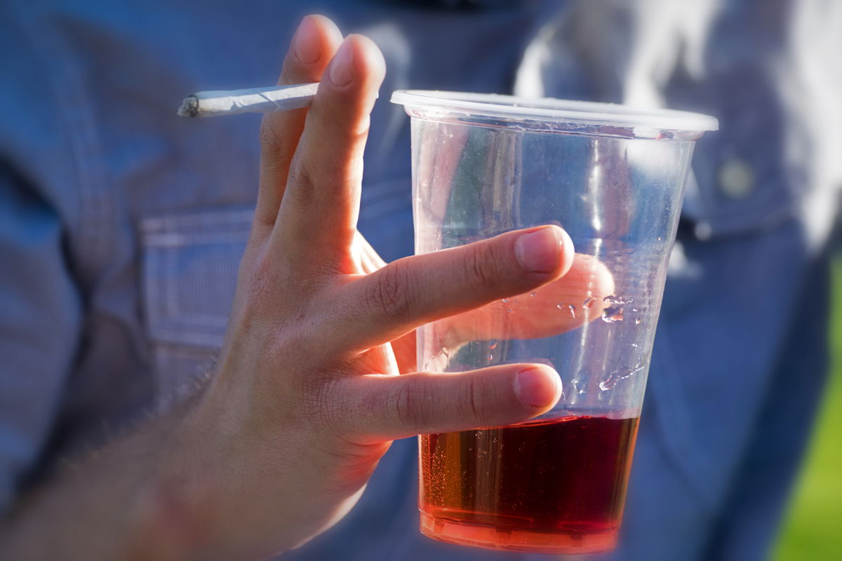 <i>Adobe Stock</i><br/>A person drinks an alcoholic beverage while smoking cannabis. Adults who reported using cannabis and alcohol also said they drove under the influence of these drugs