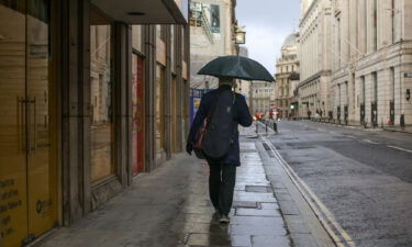 A morning commuter carrying an umbrella while walking through the City of London