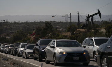 Motorists wait for a signal to change as pump jacks extract oil at the Inglewood Oil Field Thursday