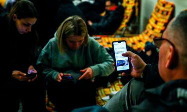 Passengers are checking their mobile phones inside a building of the railway station after arriving on a train from Kiev in Ukraine to Przemysl