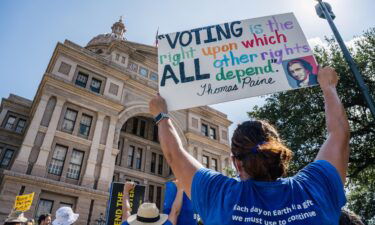 People display signs during the Georgetown to Austin March for Democracy rally on July 31