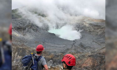 Researchers look down at Laguna Caliente after climbing out of the crater.