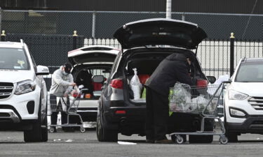 Two people load their cars with groceries in the parking lot of a Chinese supermarket in the Elmhurst neighborhood of the Queens borough of New York City on January 13.