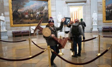 Adam Johnson carries the lectern of Speaker of the House Nancy Pelosi through the Rotunda of the US Capitol Building after a pro-Trump mob stormed the building on January 6