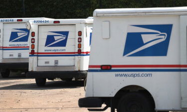 United States Postal Service (USPS) trucks are parked at a postal facility on August 15